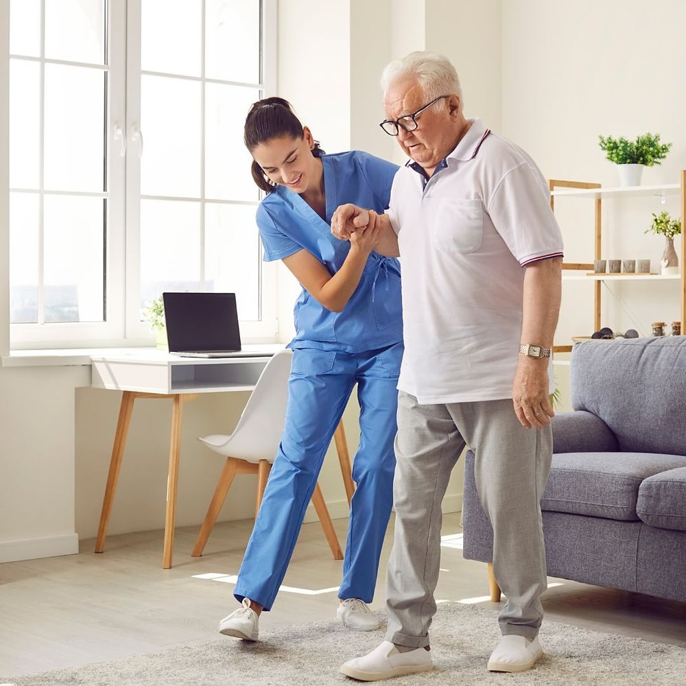Support worker helping an older man walk at home